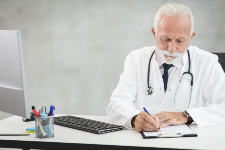 Physician writing on a clipboard at a practice desk, illustrating a medical equipment leasing review